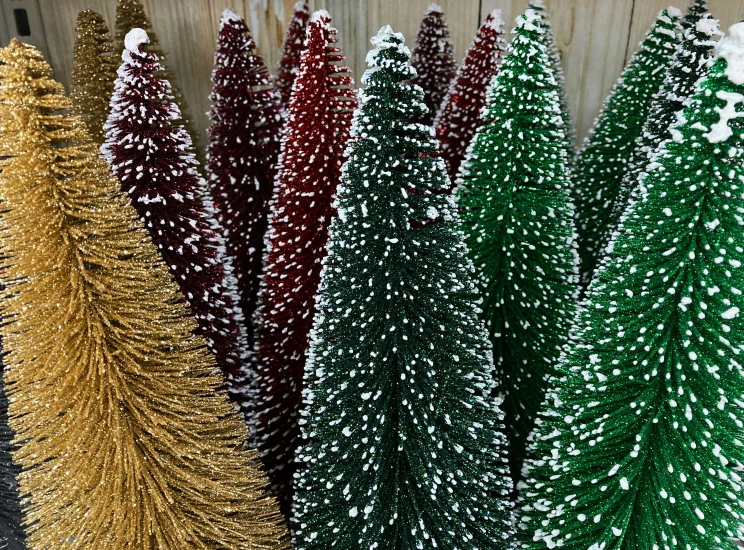 three small christmas trees are on display in front of a wooden wall
