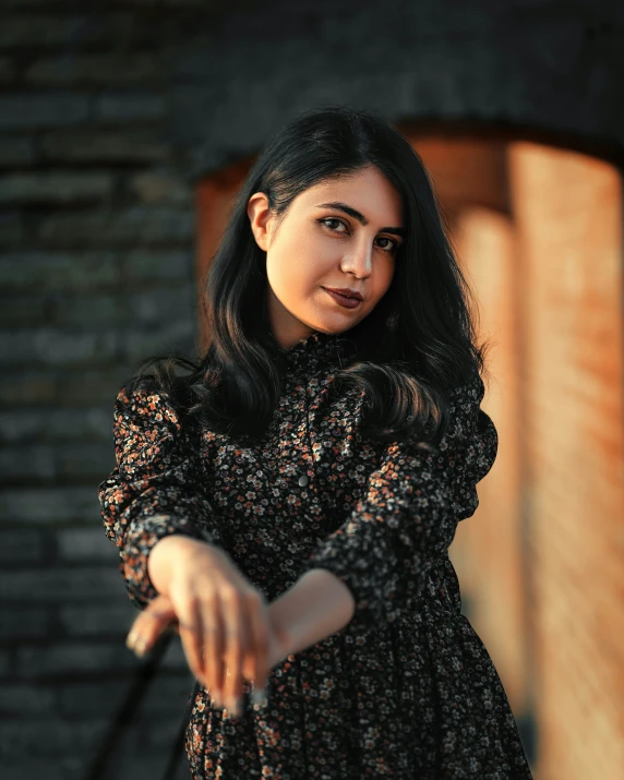 the woman poses for the camera by some old brick building