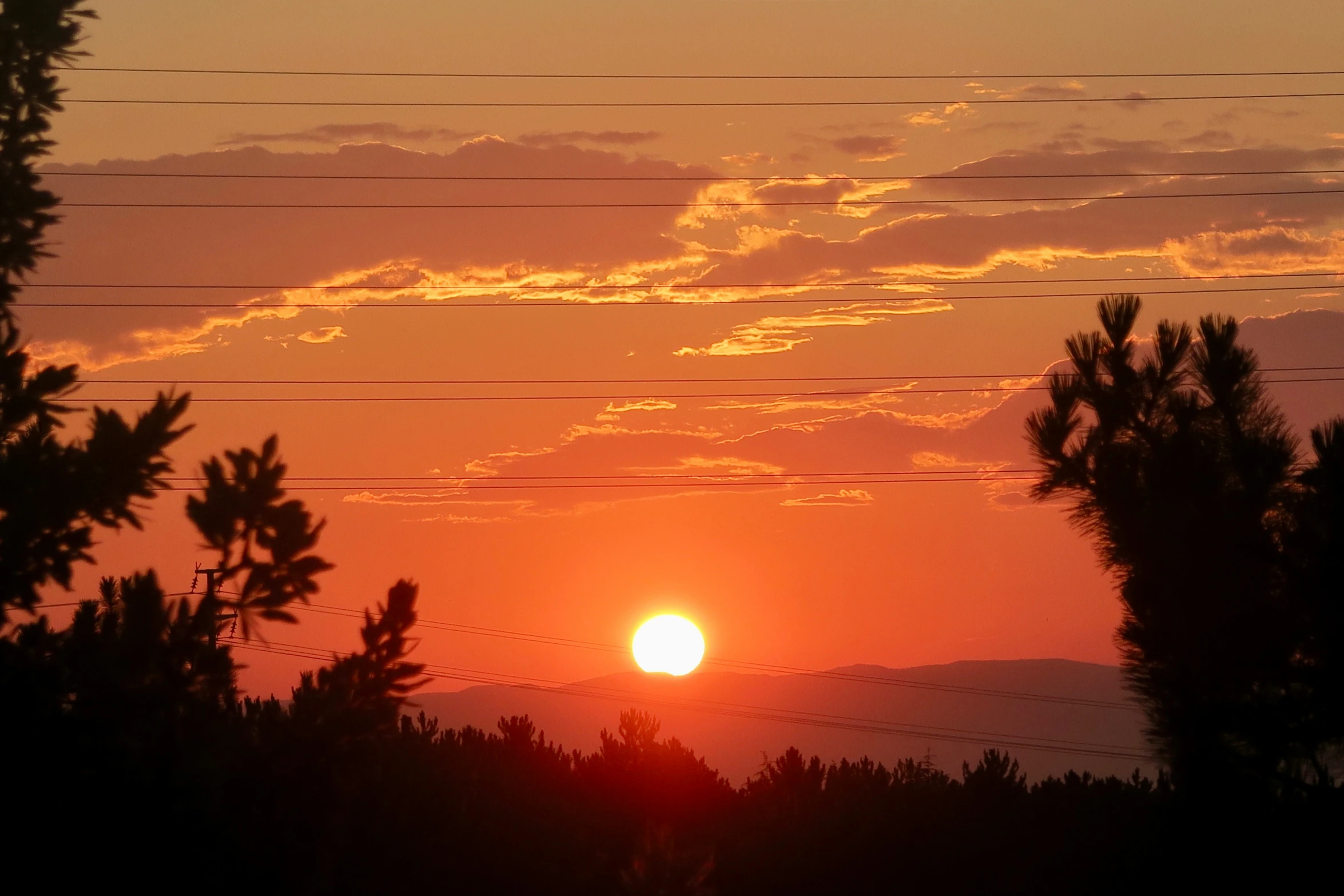 sunset in front of mountain and electrical lines