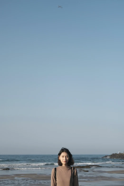 a woman stands on a beach looking into the distance