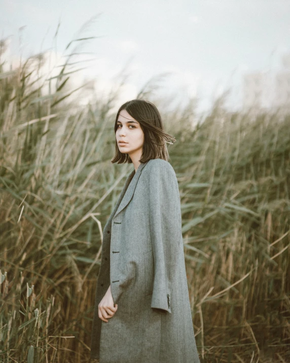 a woman standing in tall grass, her head facing the camera