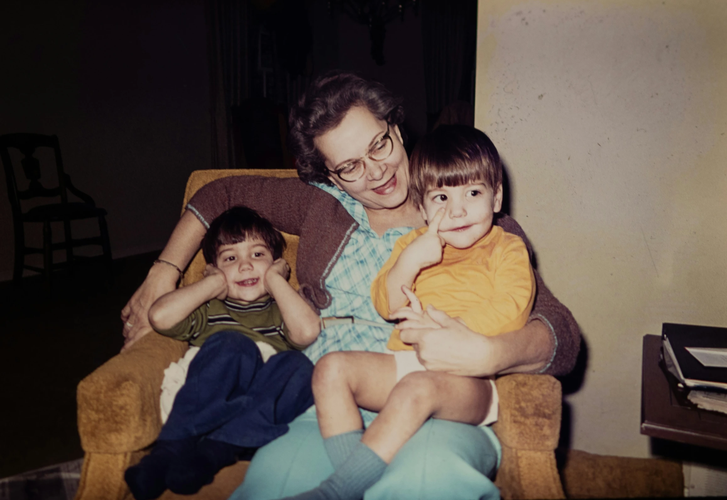 woman sitting on couch holding small children and smiling