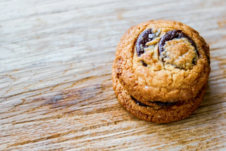 a cookie sits on a wooden table looking around