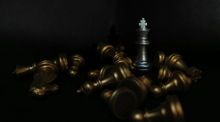 a bunch of metallic chess pieces on a black background