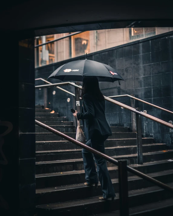 person walking up stairs with umbrella in hand