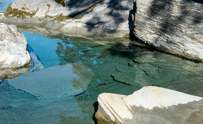 the rocks are reflecting in the water, so you can see some birds in it