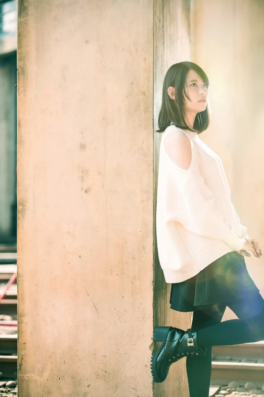 a woman with knee boots, leaning against a wall