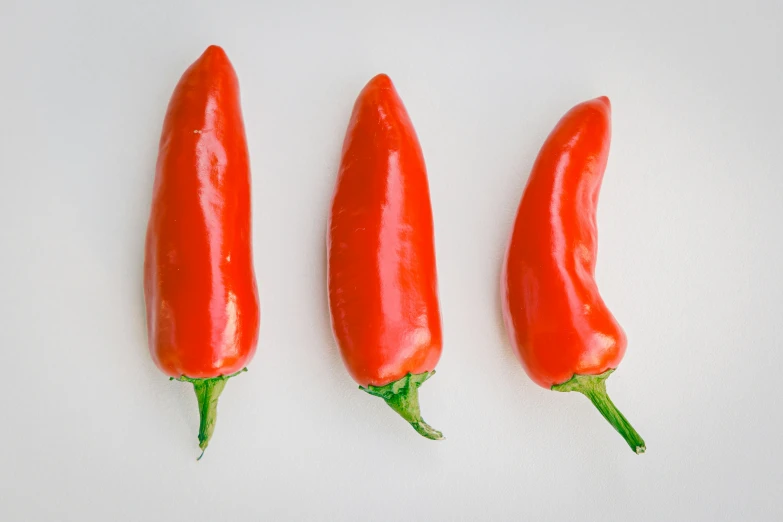 three chili peppers placed next to each other on a white surface