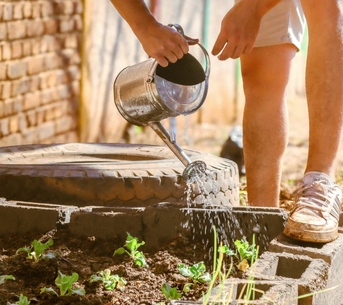 a man is holding a watering can as he waters the plants