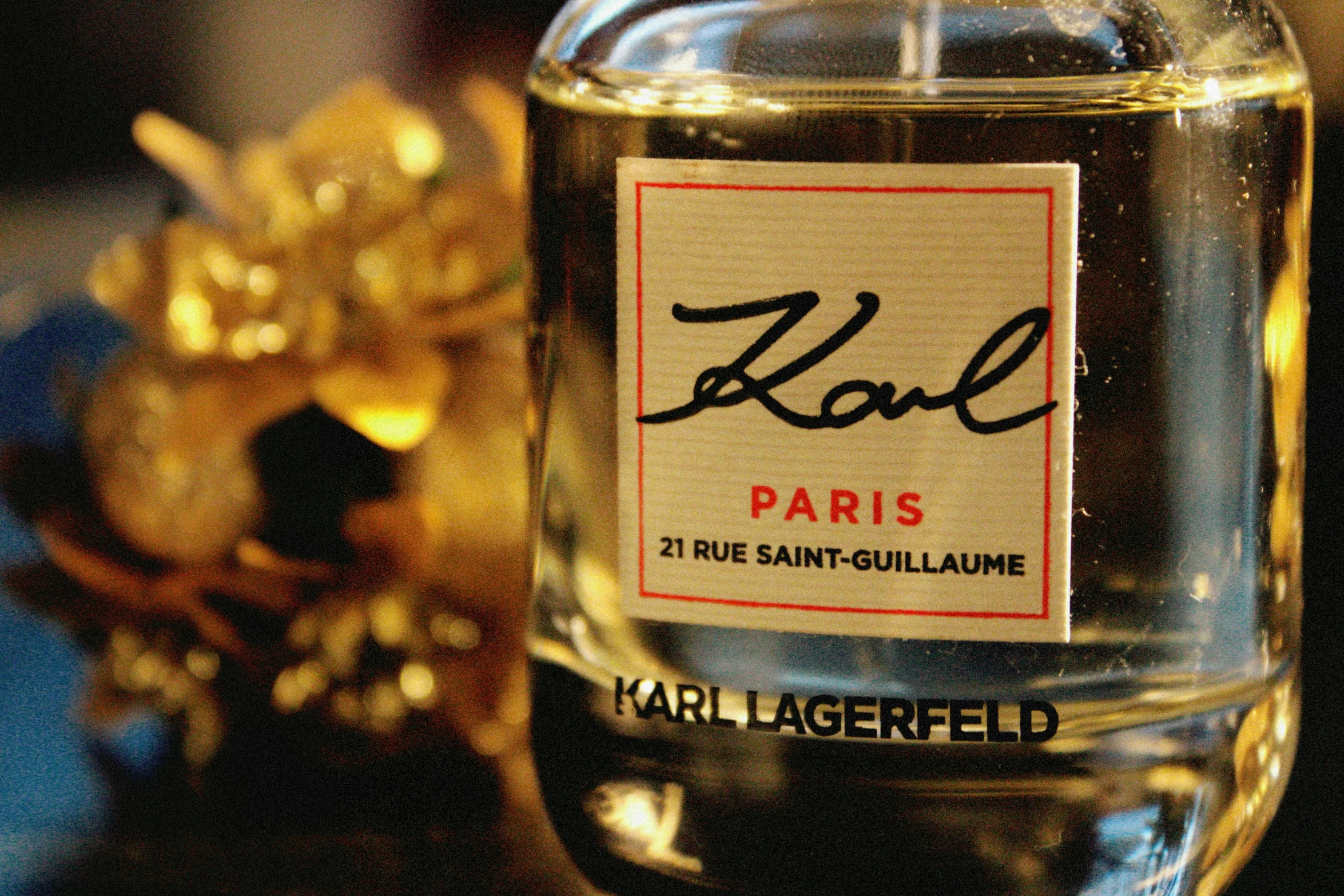 the label on a glass bottle with gold flower decorations in the background