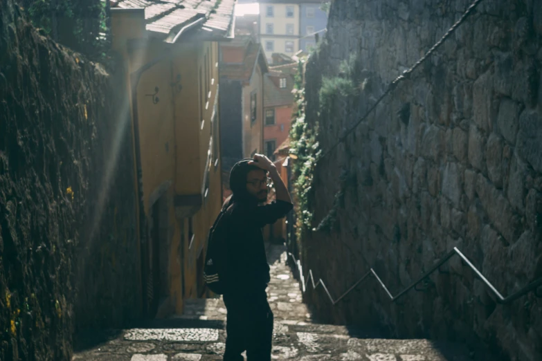 a person taking a picture while walking down a narrow street