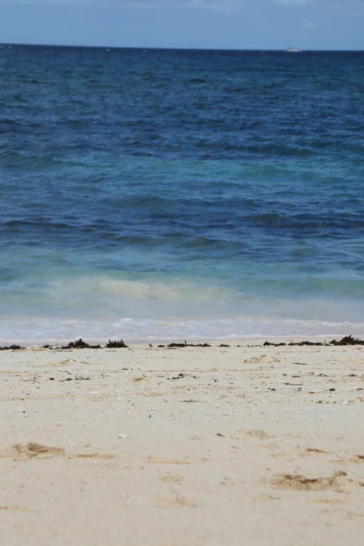 the ocean is blue and clear, with some waves on the shoreline