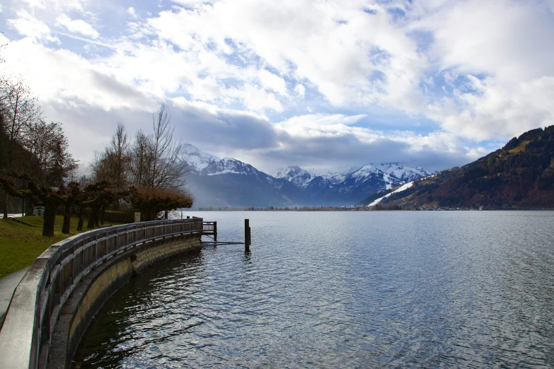 a body of water surrounded by mountains under a cloudy sky