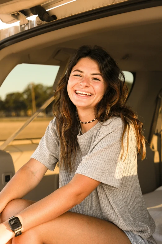 a woman sitting on the back of a car smiling