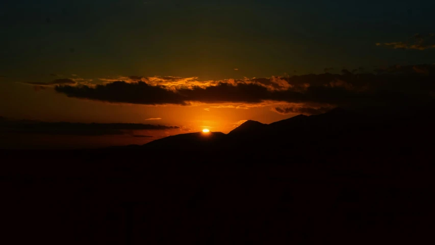 a sunset in the sky behind mountains