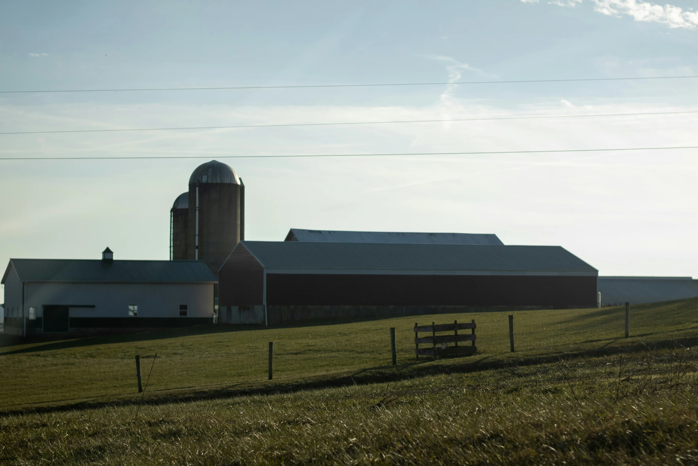 a barn on a field with two silos in the background