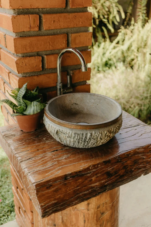 stone basin with plants on top by a wooden table