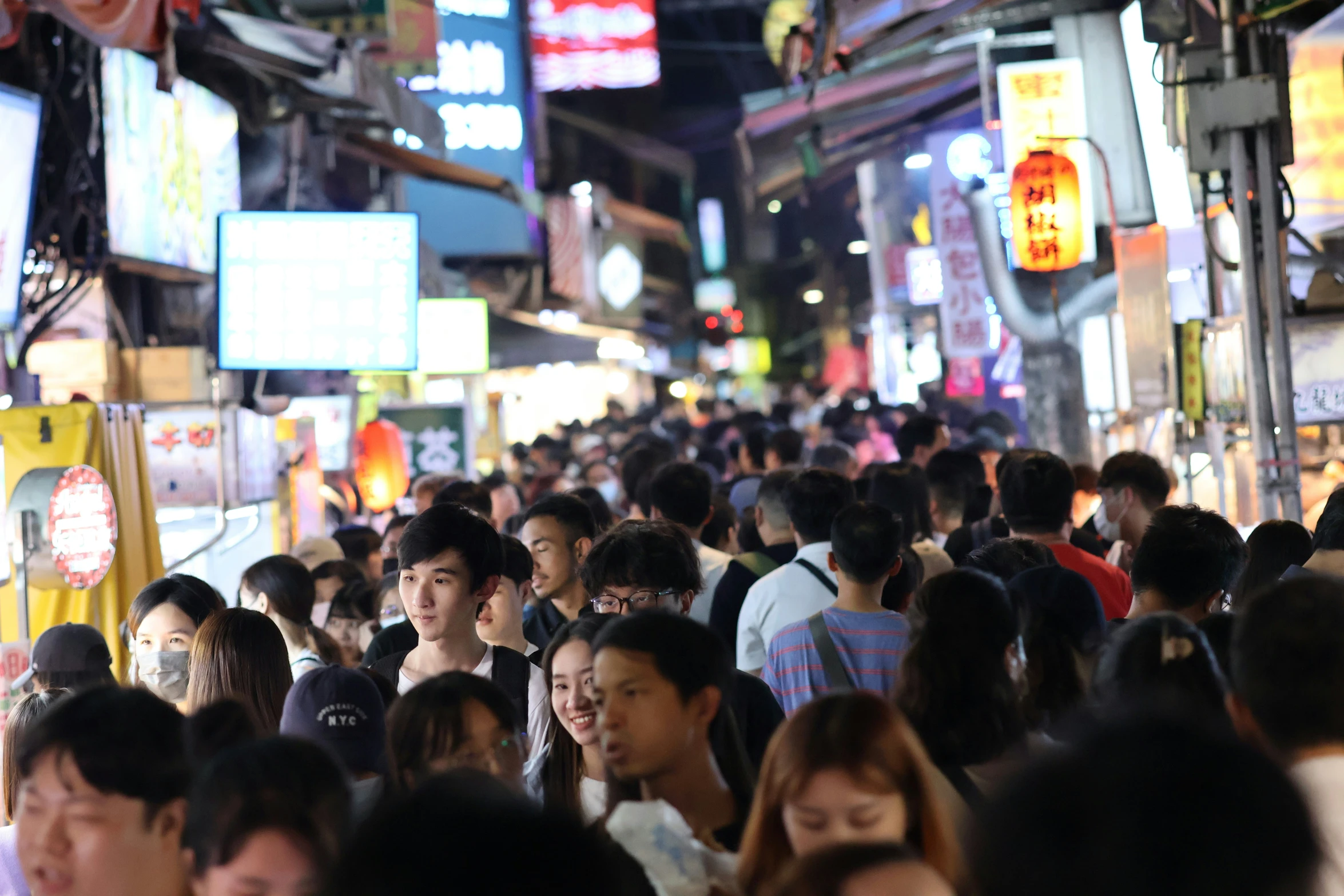 many people are walking down a crowded alley way