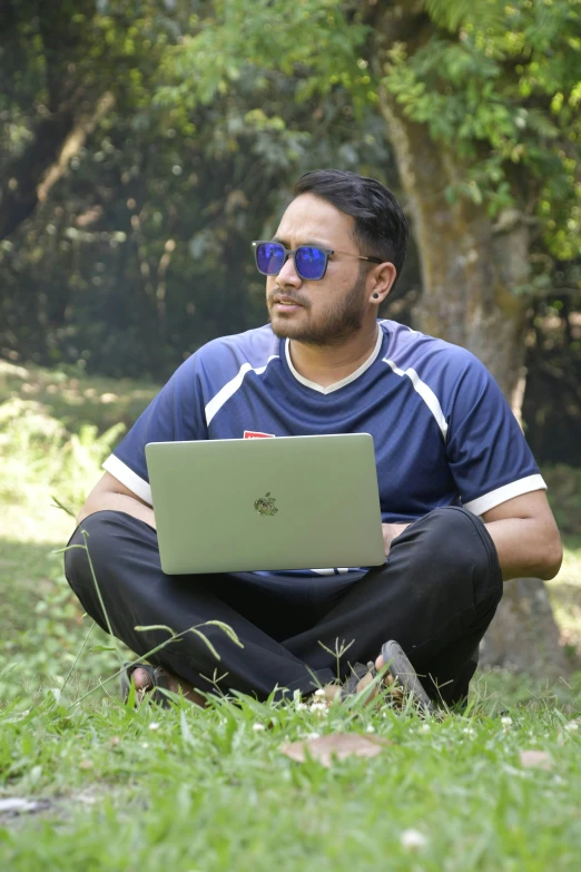 man in a blue shirt and sunglasses on a laptop