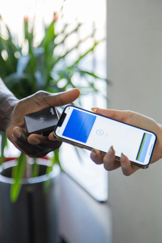 a man holds onto his cell phone while another person uses it to touch it