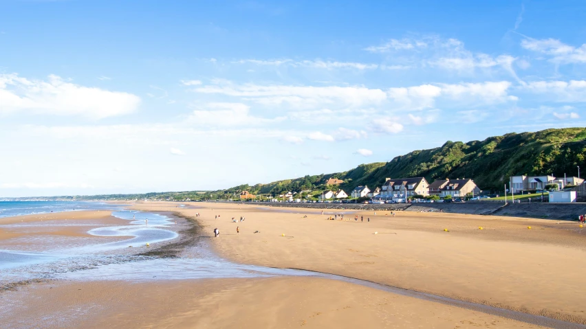 a beach with people walking on it under a blue sky