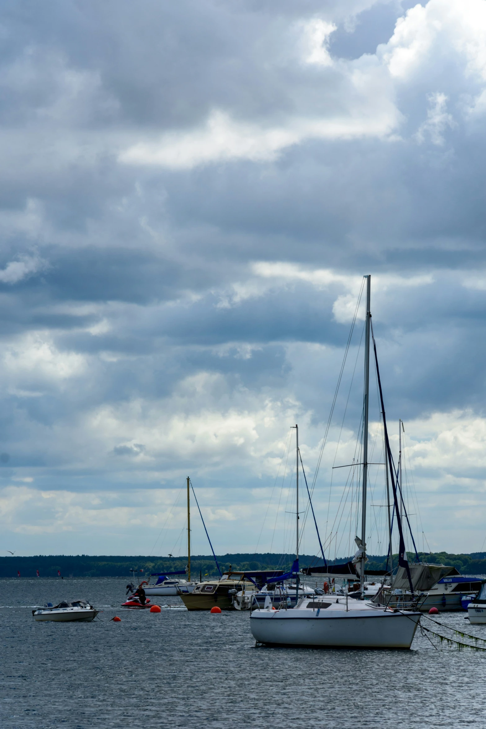 sail boats docked on the water under cloudy skies