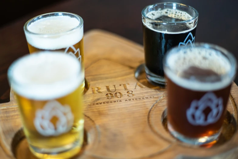 three beers sit in front of each other on a wood tray