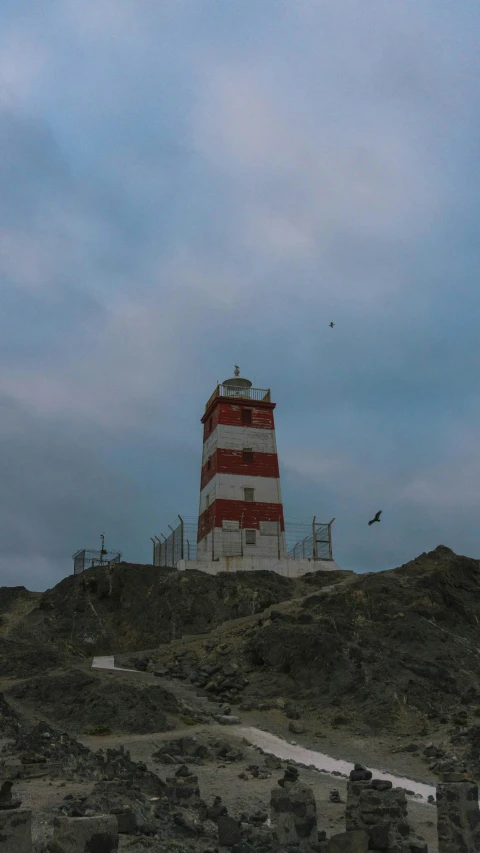 a lighthouse is on top of a hill with a blue sky in the background