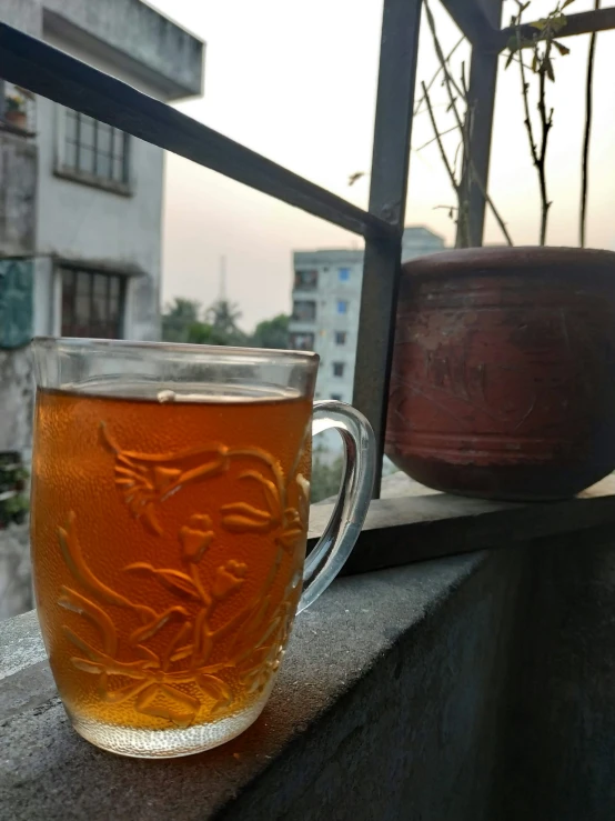 a glass mug sitting on a ledge looking out to the city