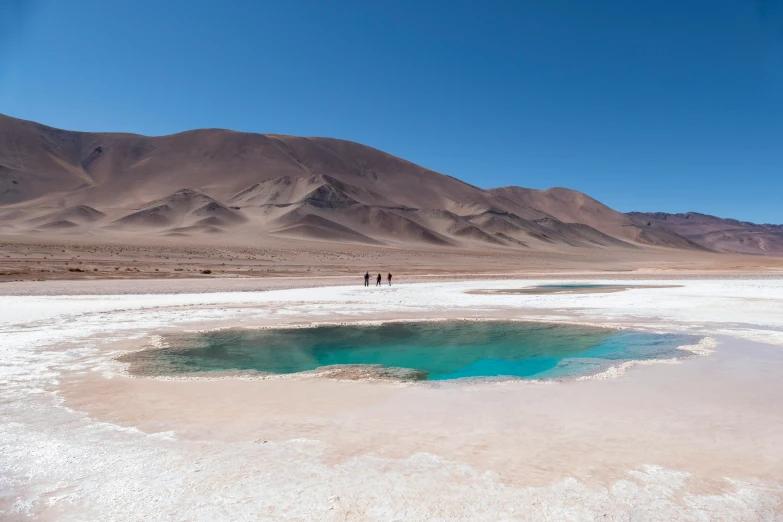 two people are standing by a lake in the desert