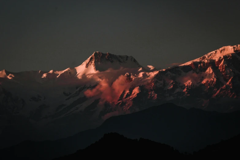 some snow capped mountains with red and white clouds