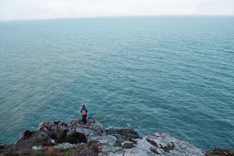 a man standing on the edge of a cliff with a person watching