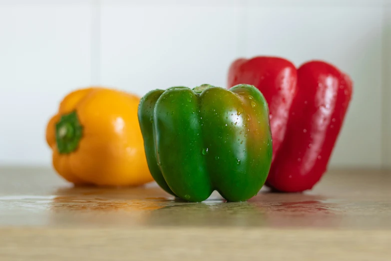 three bell peppers on a table next to a yellow pepper