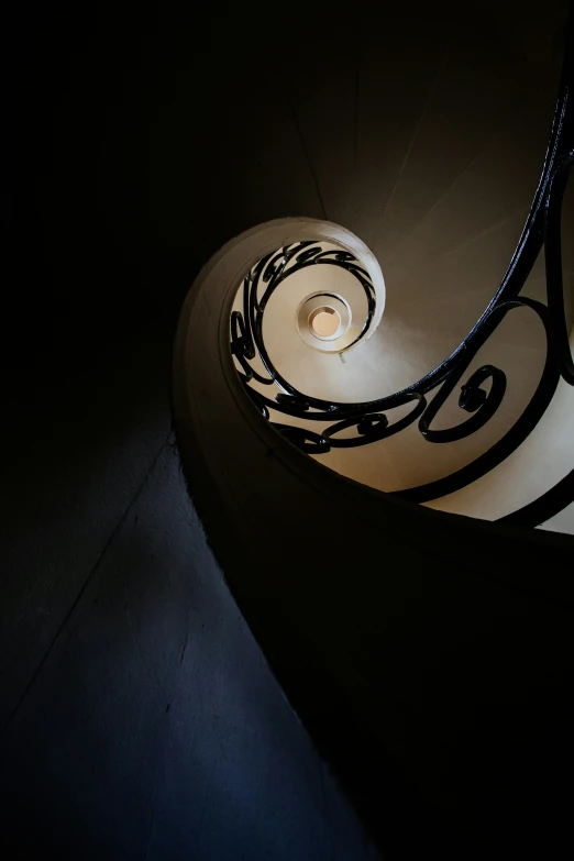 a spiral staircase in a dark building with a light shining on the floor