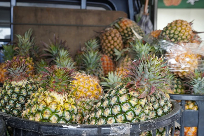 several pineapples are in the bins outside on a market