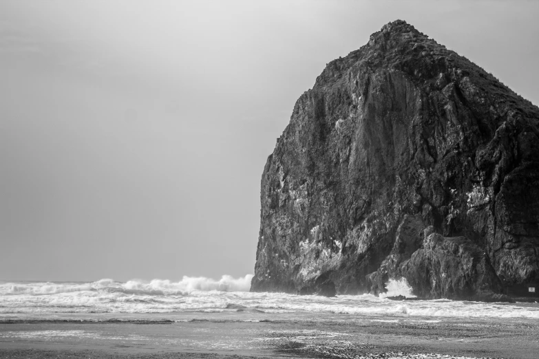 a very tall rock out in the ocean near water