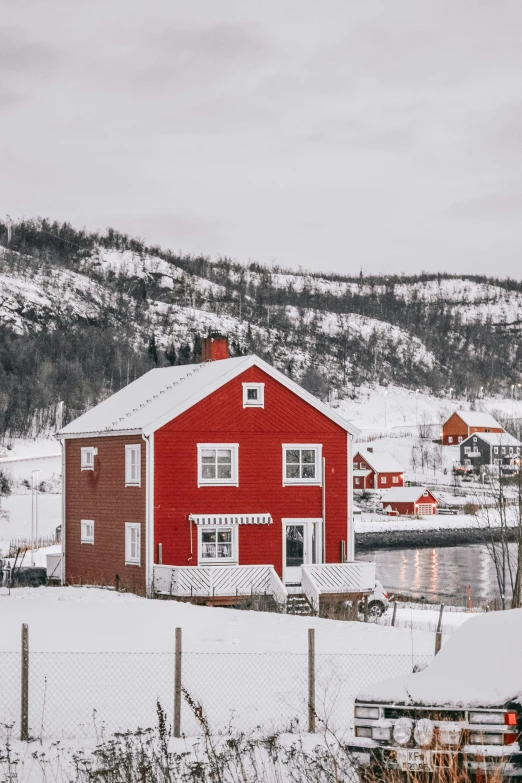 a red barn sits on a hill near the water