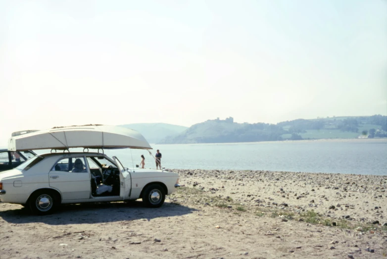 two cars with an umbrella at the front of them, parked in sand