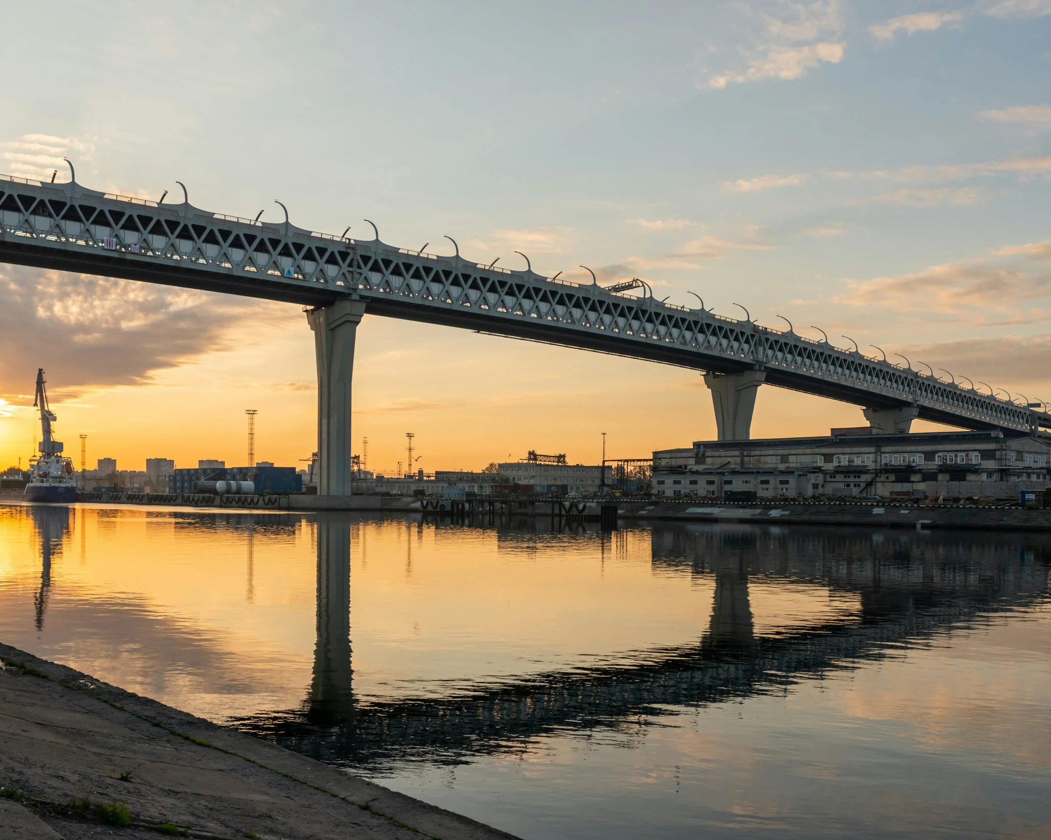 bridge over the water at sunset with buildings and light clouds