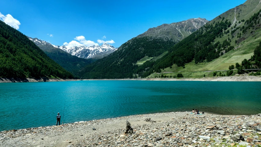 people are walking by the water and the mountains