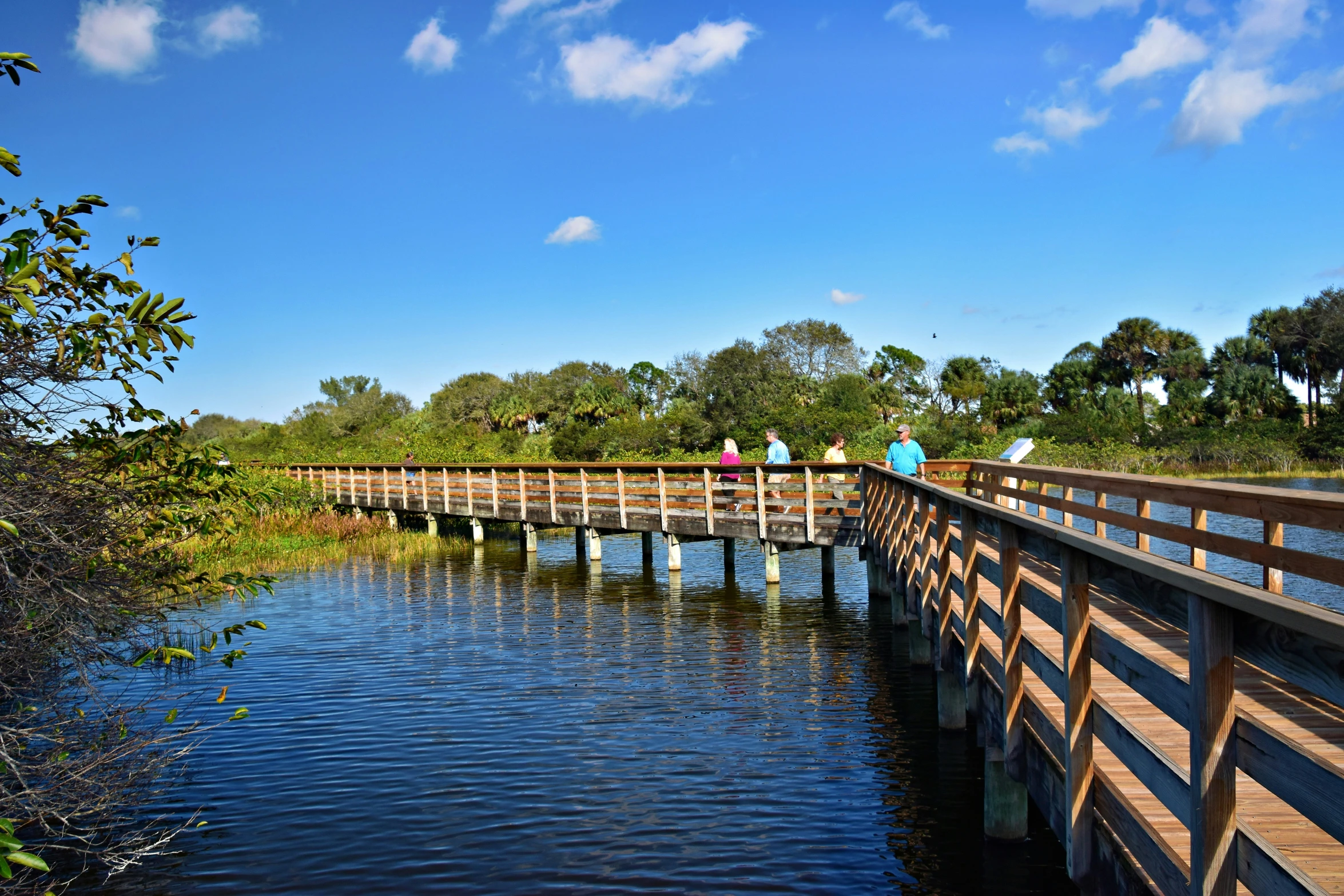 people are walking over a wooden bridge