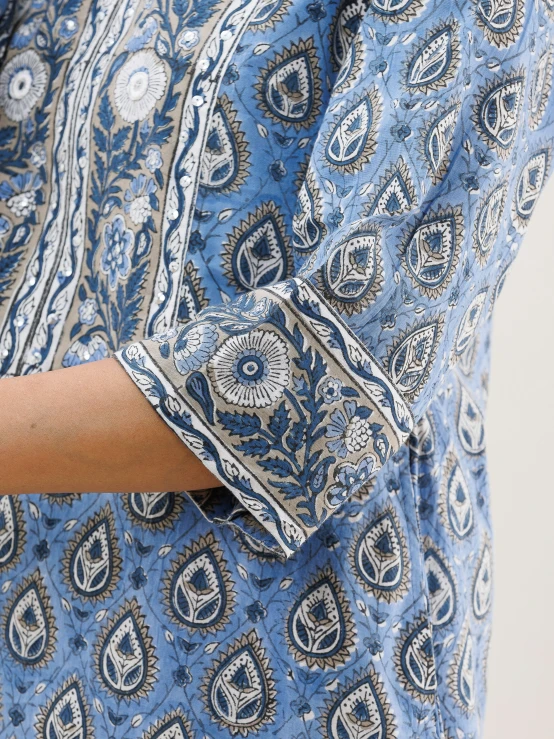 the arm of a person wearing blue paisley dress