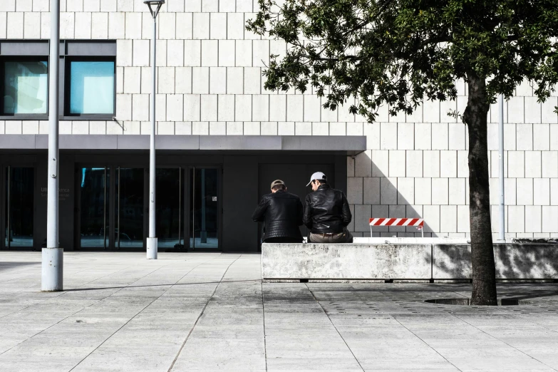 two people with black jackets in front of a tall building