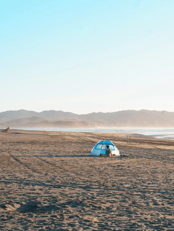 the tent sits on the beach in front of the mountains