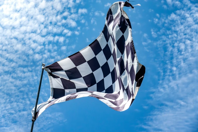 a flag flying in the wind with a blue sky background