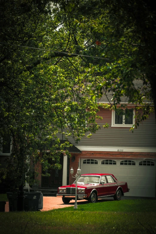 a red car parked next to a driveway and two cars