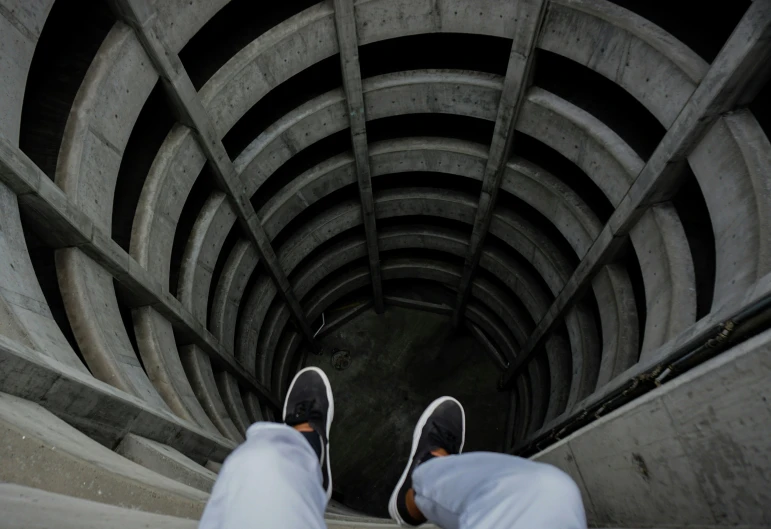 a person's feet standing on the edge of a tunnel