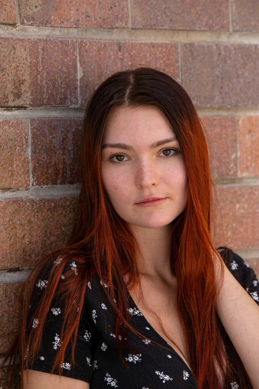 a young woman posing in front of a brick wall