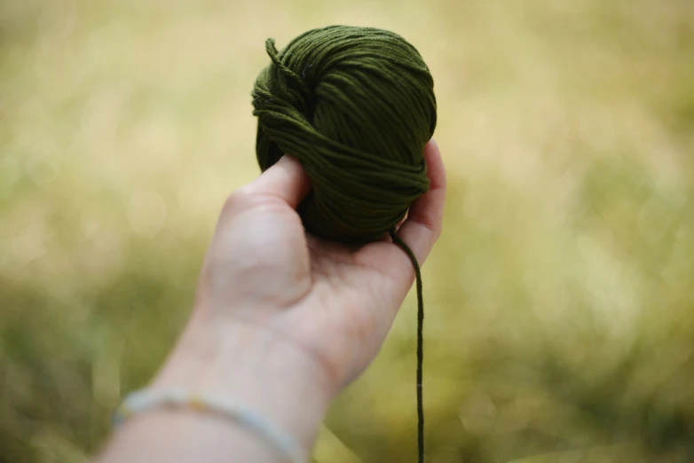 a green ball of yarn in someone's hand