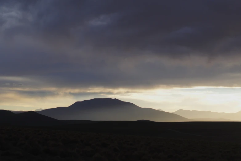 a distant mountain rises above some trees at dusk